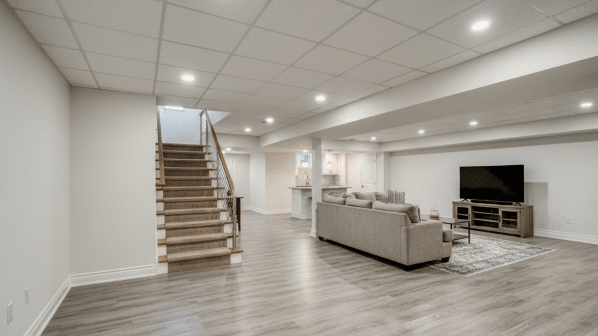 finished basement with open family room, TV area, recessed lighting, and staircase access.