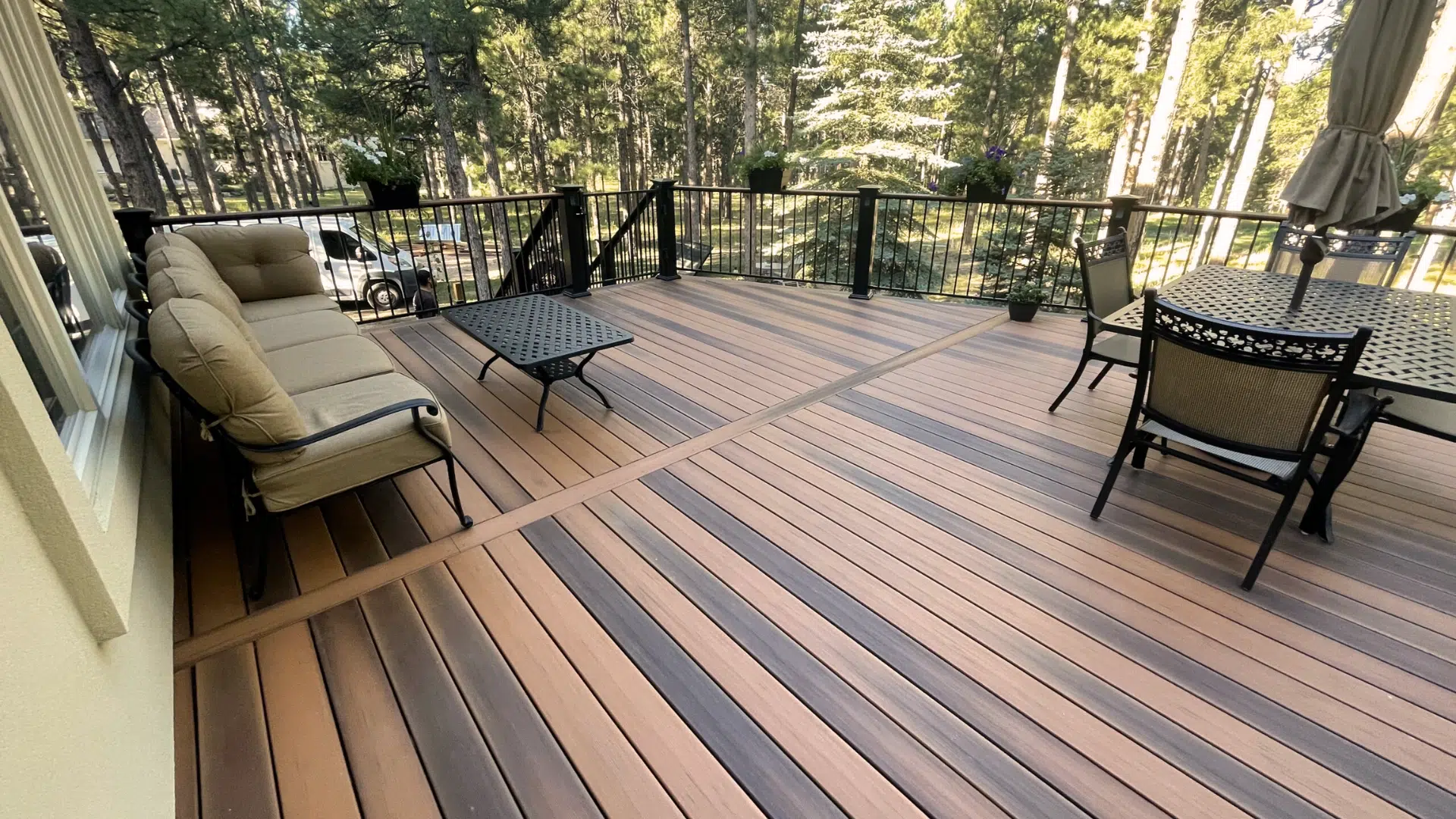 low-maintenance composite deck boards with outdoor seating and dining area in a wooded backyard.