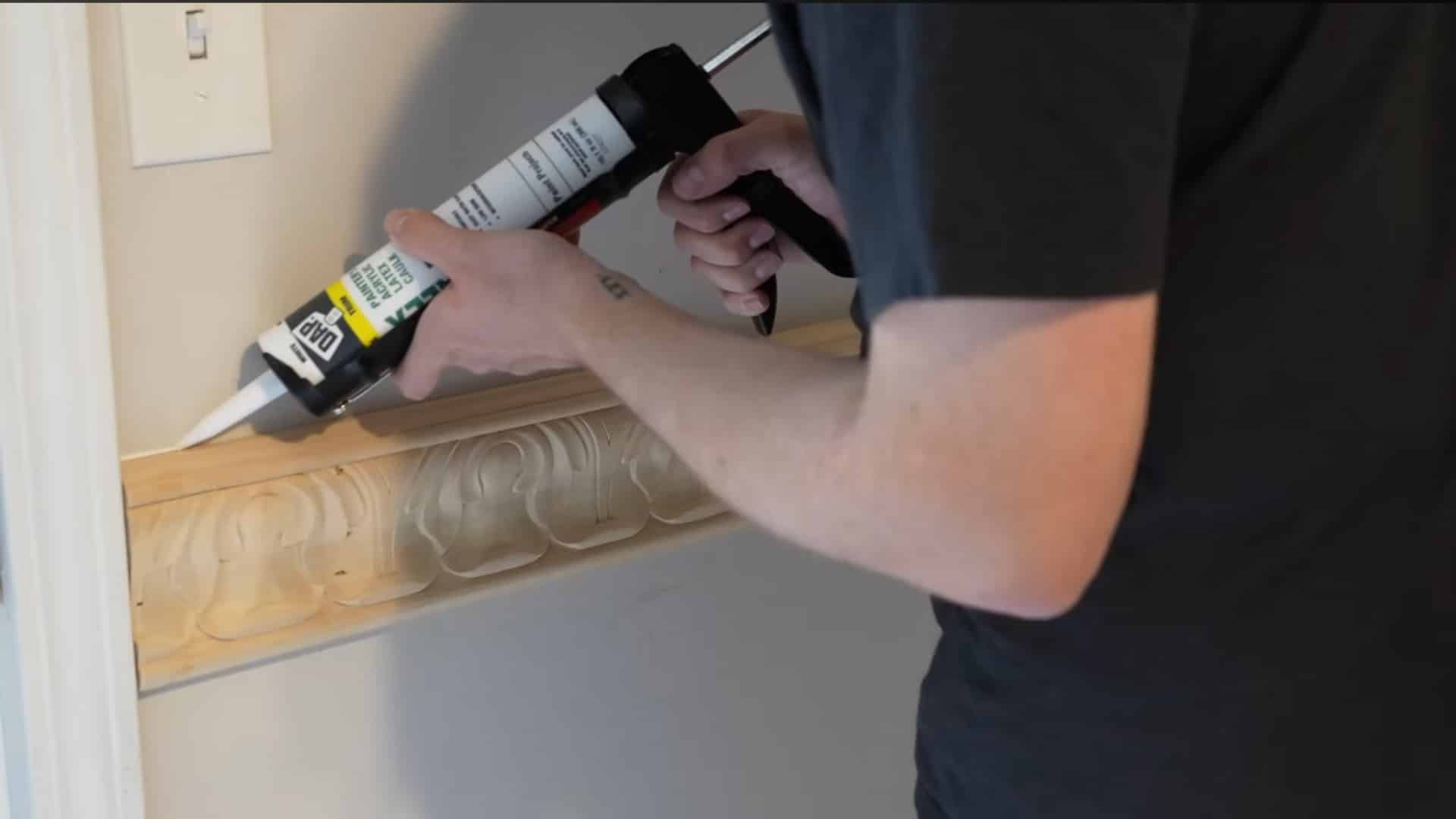 worker sealing the edges and nail holes of decorative chair rail molding with caulk