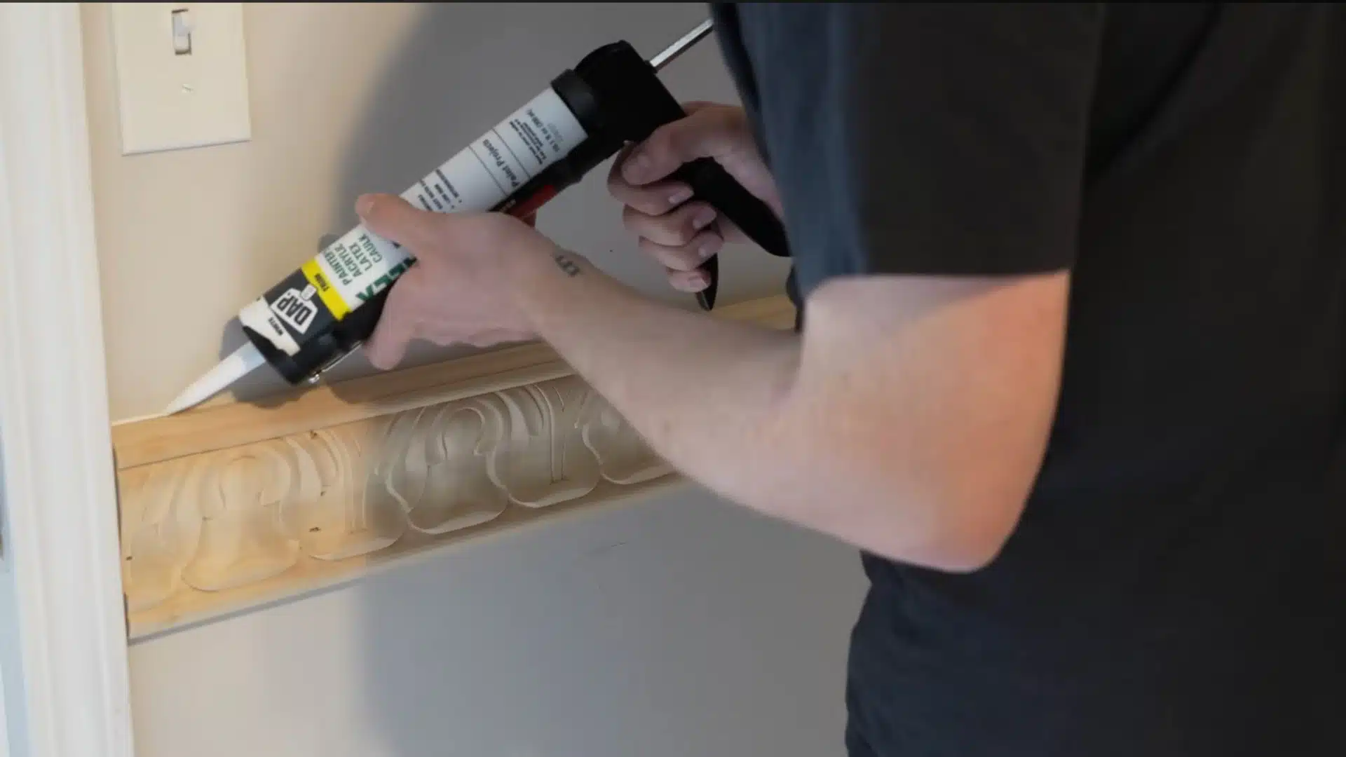 worker sealing the edges and nail holes of decorative chair rail molding with caulk