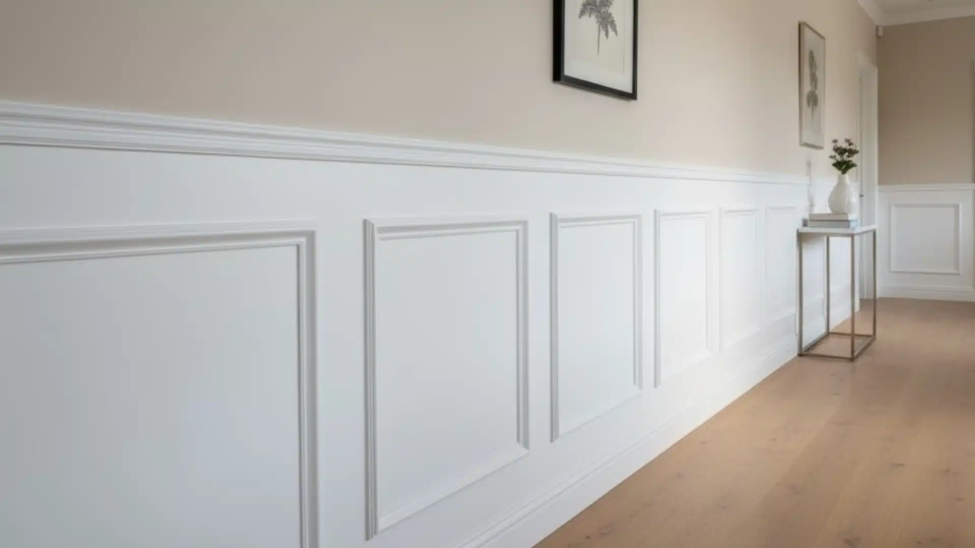 bright hallway with white paneled wainscoting, beige upper walls, wood flooring, and a slim console table