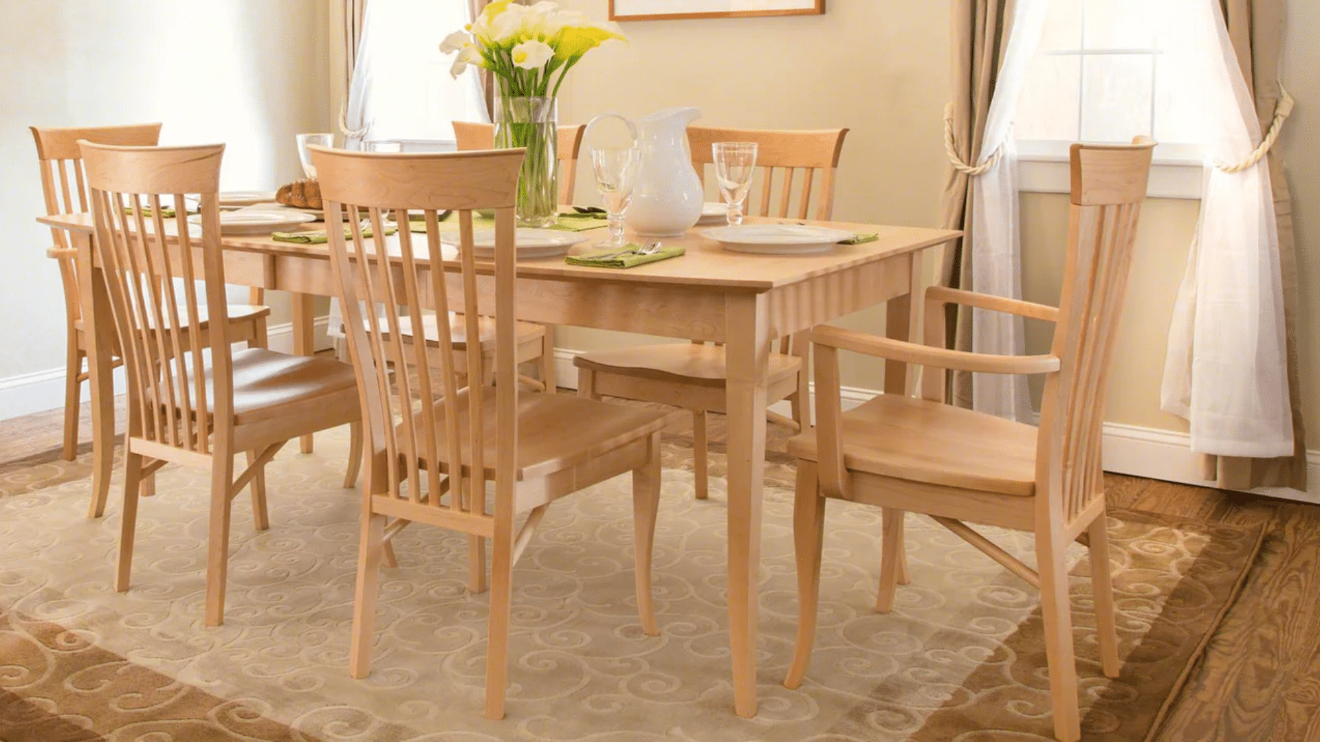 light maple dining table and matching chairs arranged in a bright dining room