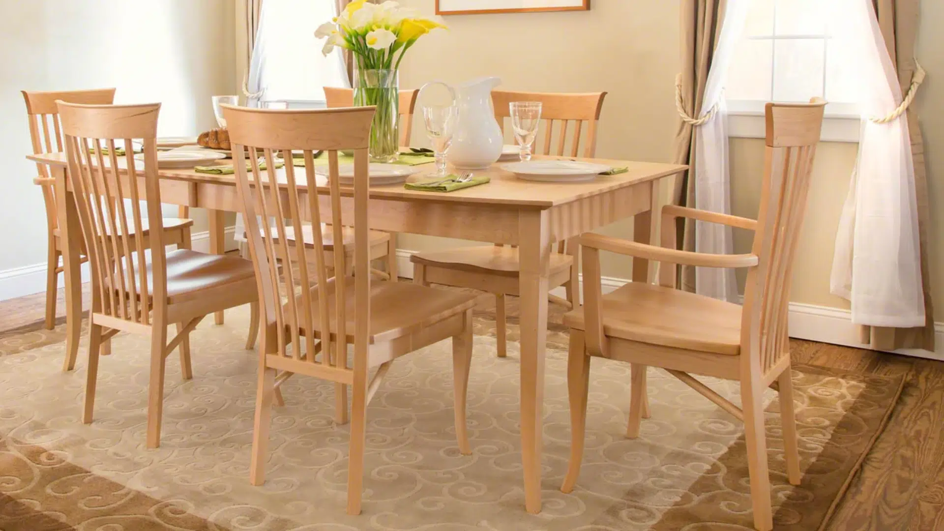 light maple dining table and matching chairs arranged in a bright dining room