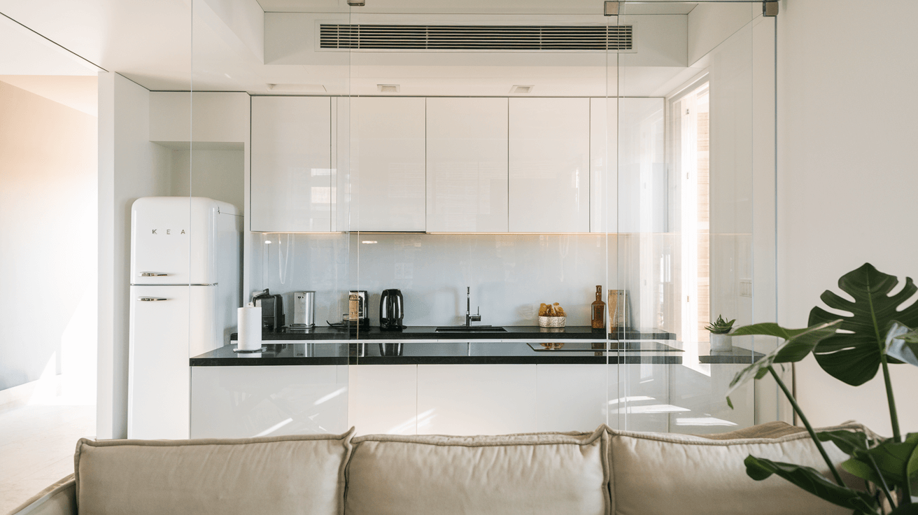 modern white kitchen separated from the living area by a clear glass partition
