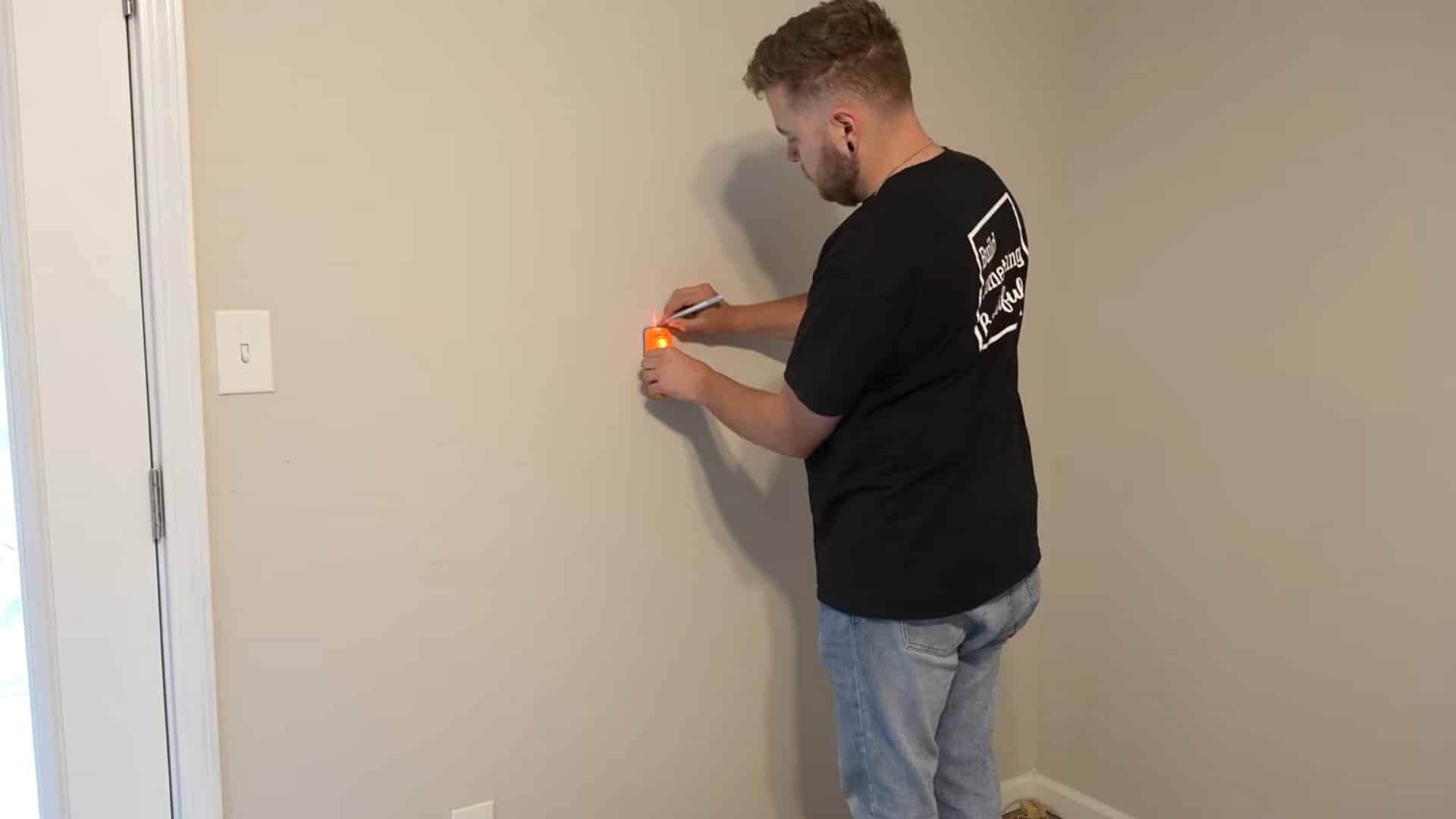 installer locating and marking wall studs before fitting wooden chair rail molding