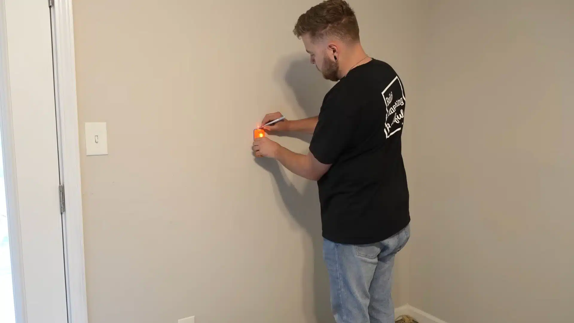 installer locating and marking wall studs before fitting wooden chair rail molding