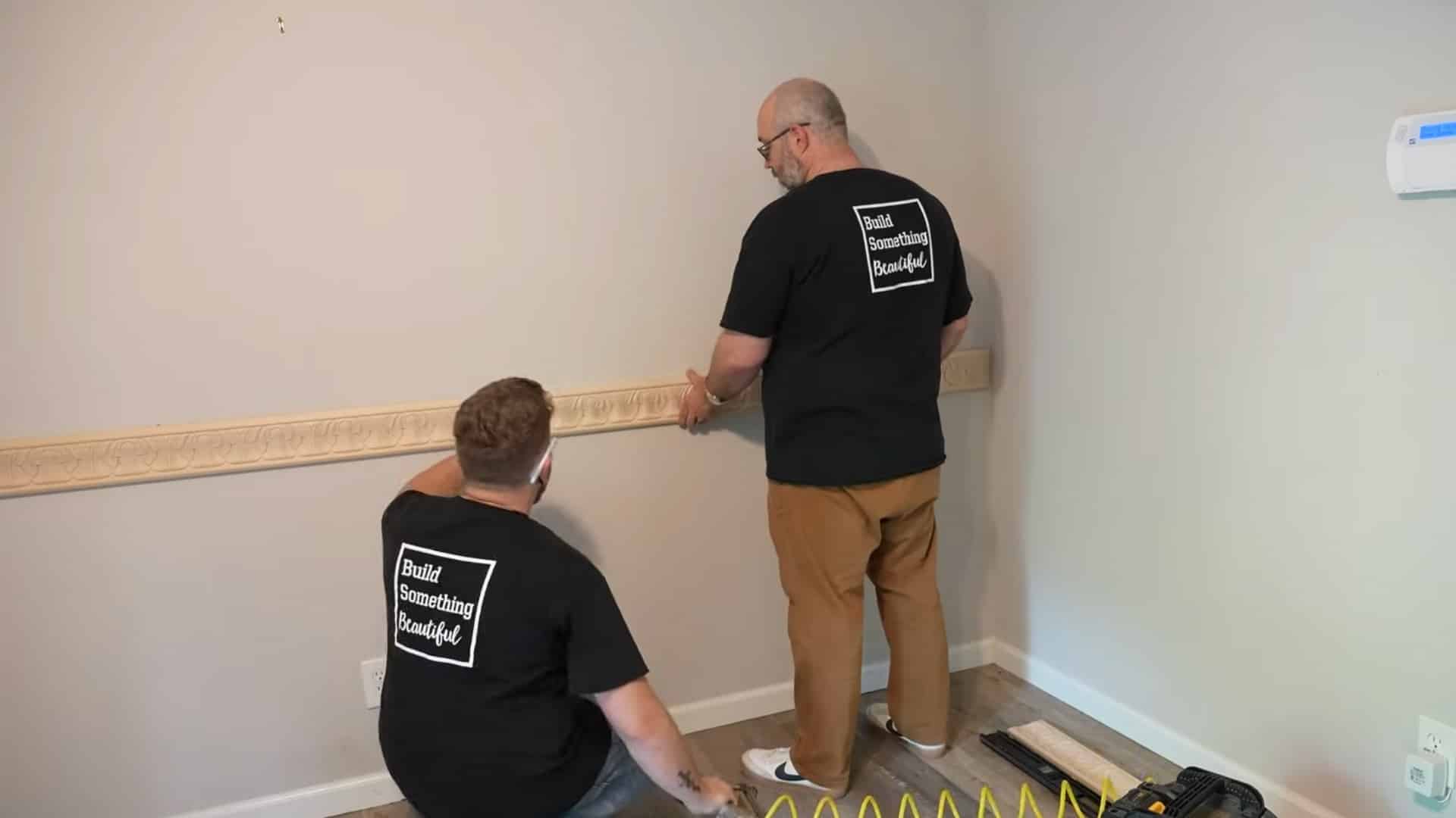 two installers aligning decorative patterns while joining chair rail molding sections