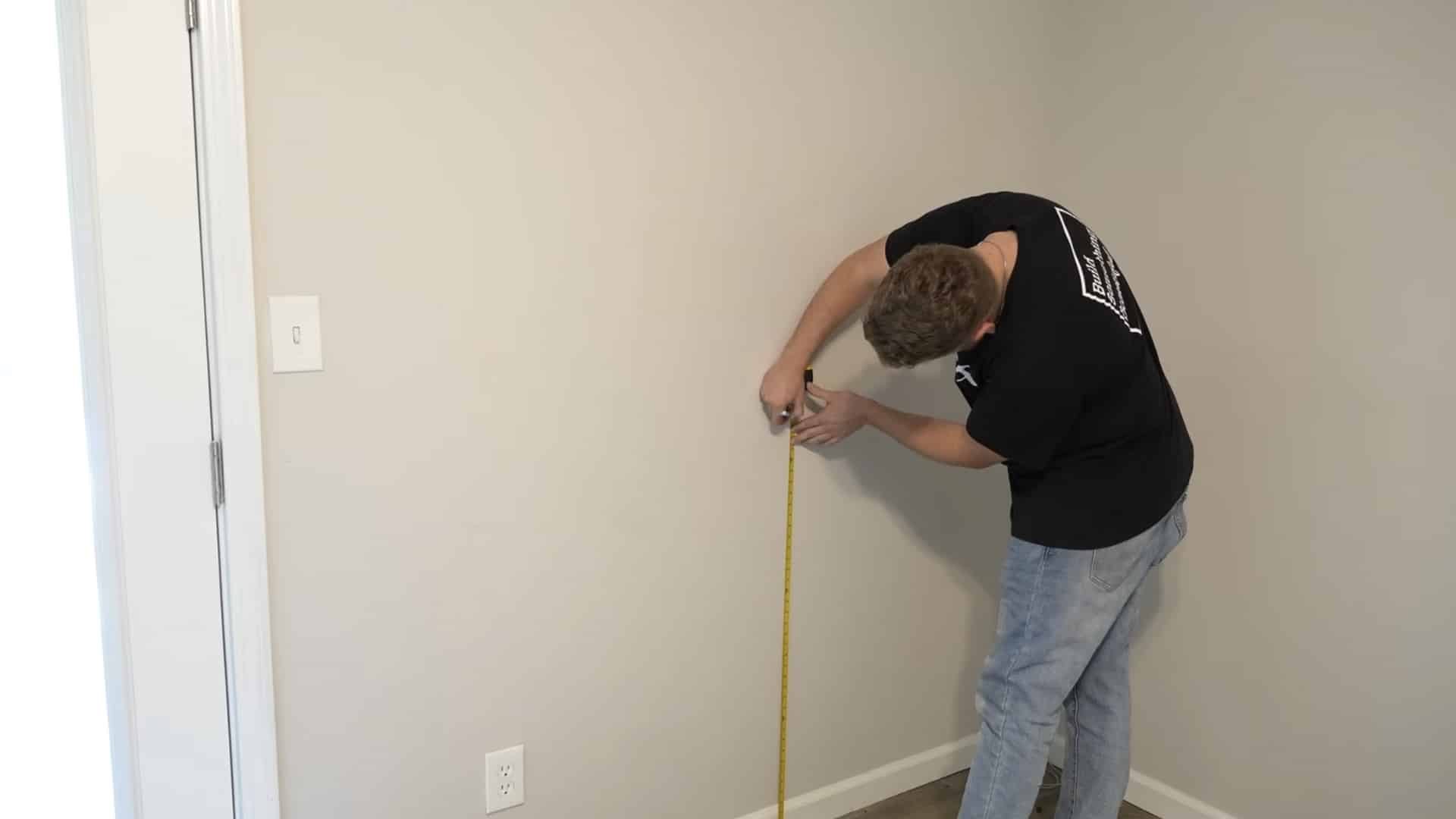 installer measuring and marking the correct chair rail height on an interior wall
