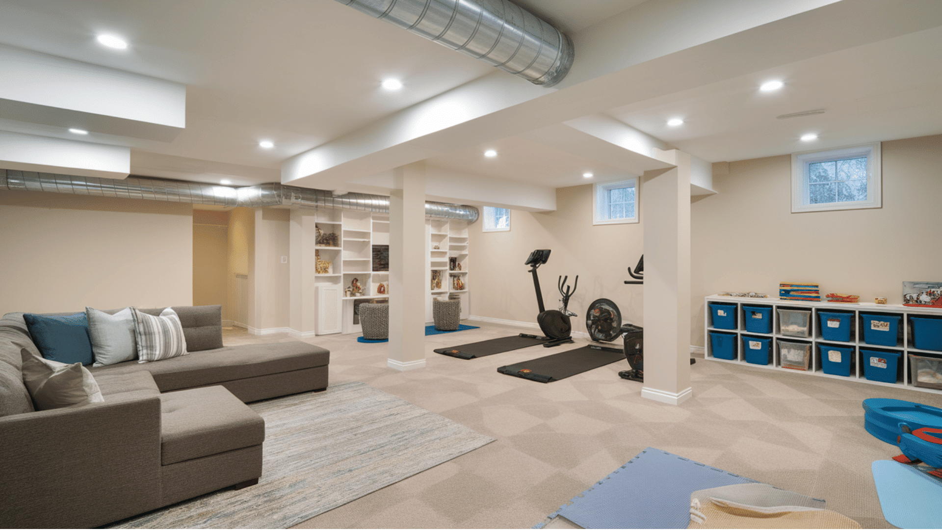 large basement divided into lounge, workout, storage, and children’s activity areas