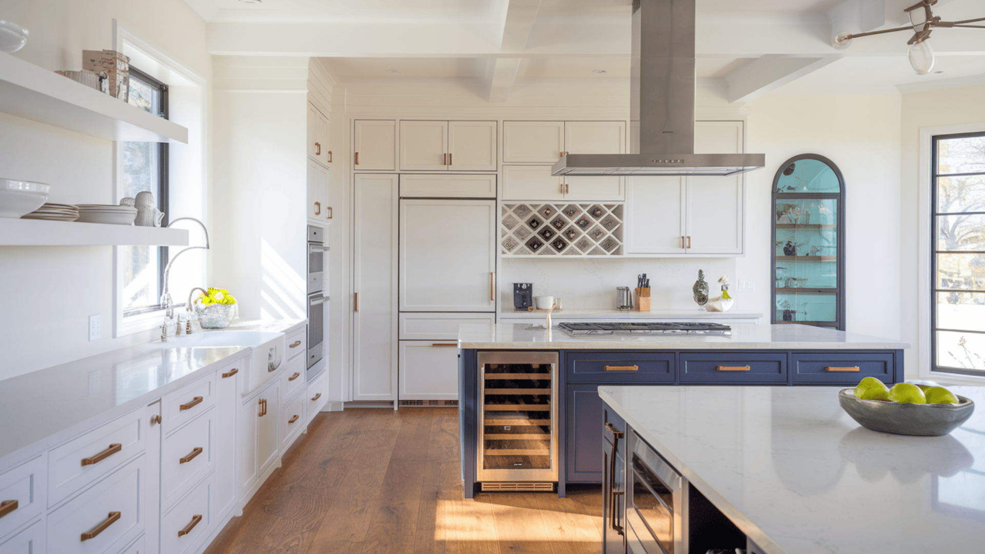 white kitchen with navy lower cabinets, glass-front uppers, and brass drawer pulls