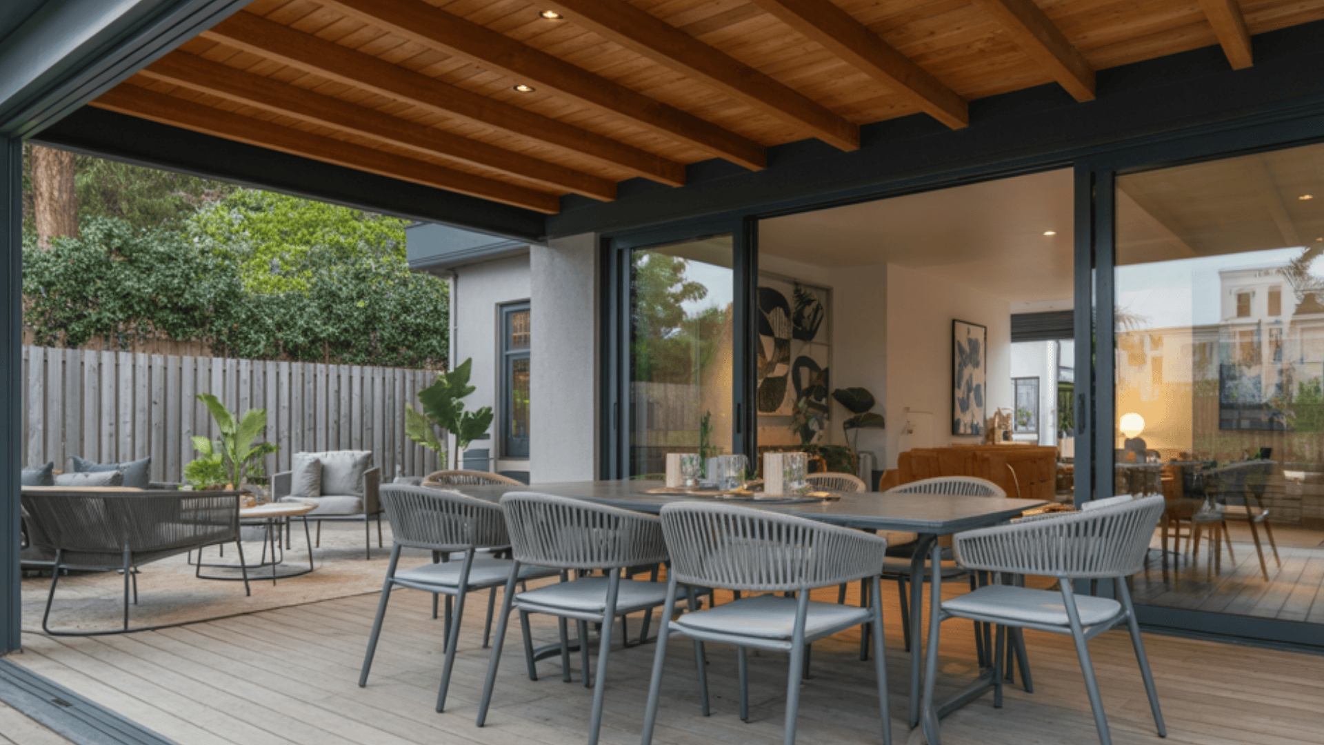 covered deck with a sloped timber roof and outdoor dining area connected to a modern home.
