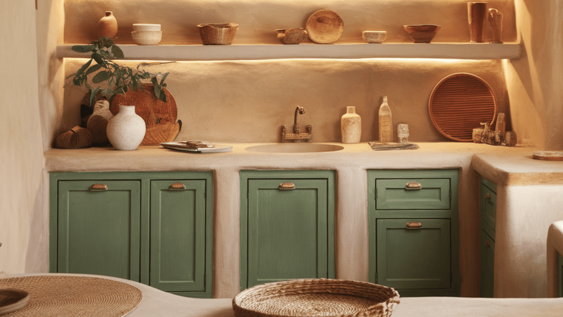 small rustic kitchen with green lower cabinets, cream walls, open shelves, and wood accents