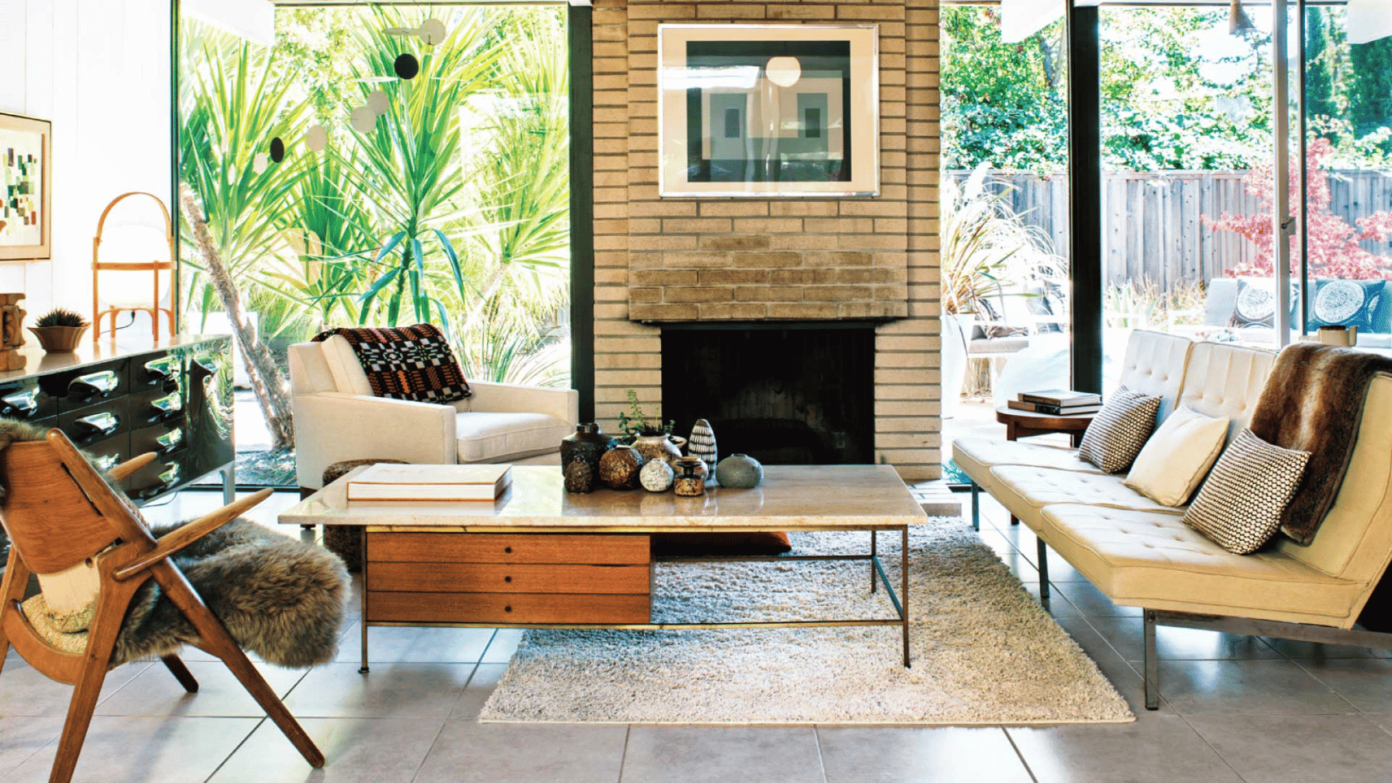 cozy rustic living room with exposed wood beams, fireplace, large windows, neutral furniture, and wooden coffee table