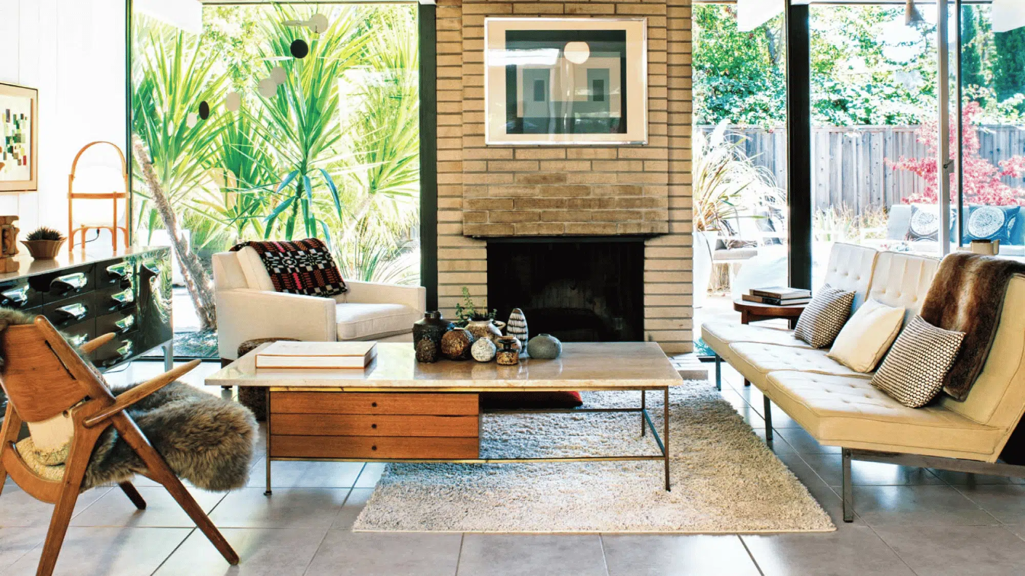 cozy rustic living room with exposed wood beams, fireplace, large windows, neutral furniture, and wooden coffee table