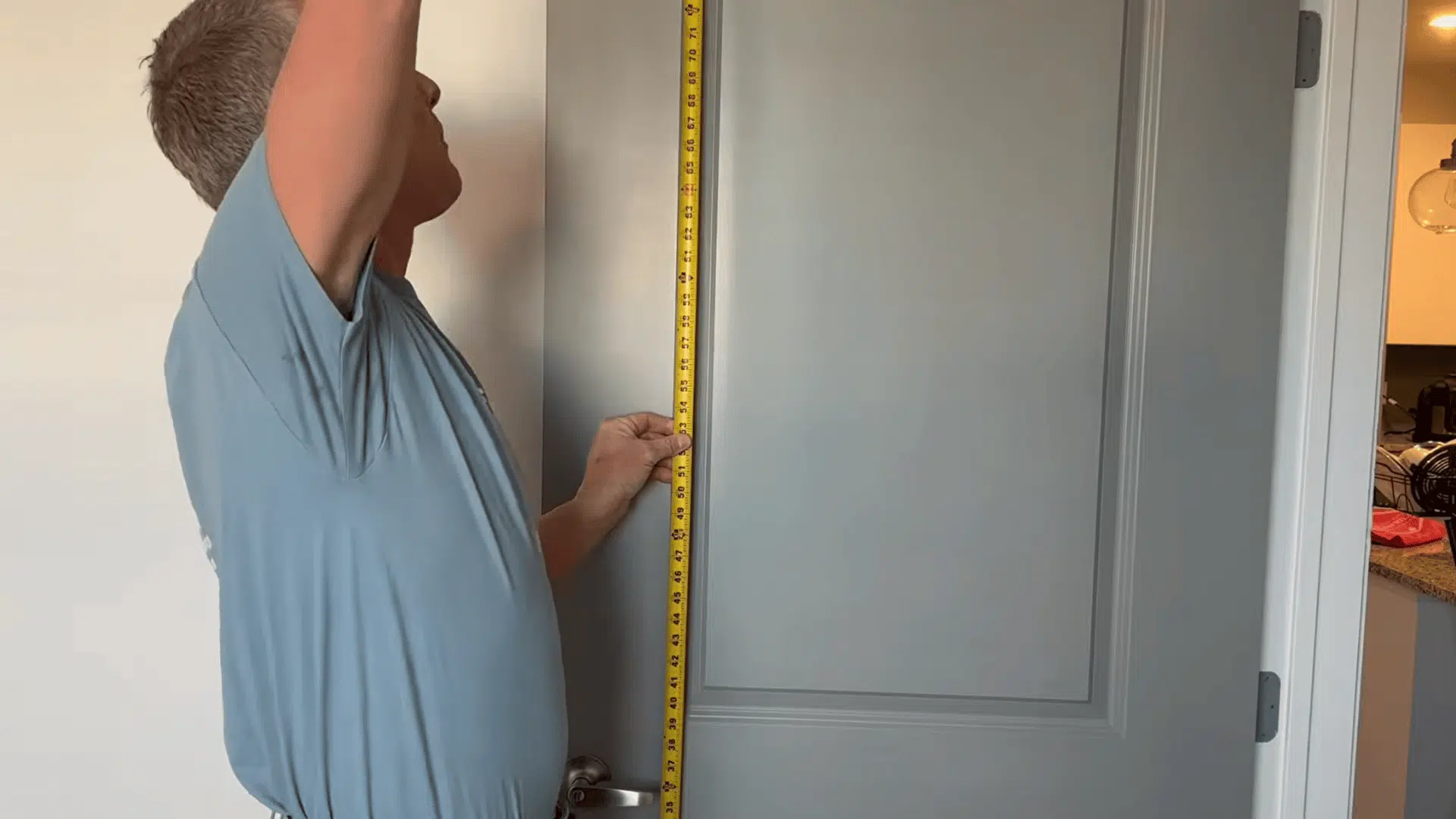 Man measuring the height of an interior door vertically with a tape measure