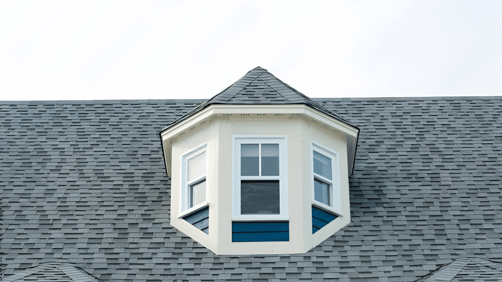 pyramidal dormer with three windows centered on a gray shingle roof